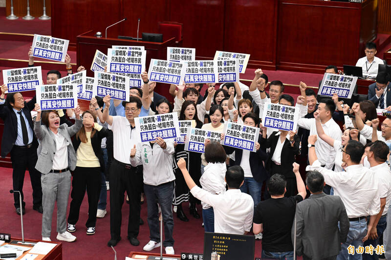 台北市長蔣萬安至議會進行施政報告及質詢，民進黨市議員紛紛手舉「蔣萬安快醒醒」的標語包圍，隨後蔣順利上台進行施政報告。（記者田裕華攝）