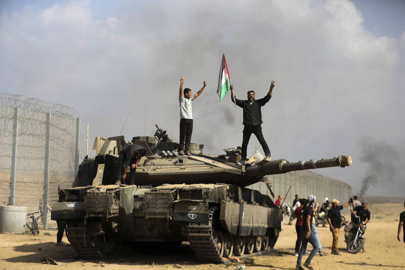 巴勒斯坦人在一輛被摧毀的以軍戰車上，揮舞巴勒斯坦旗幟慶祝。（美聯社）