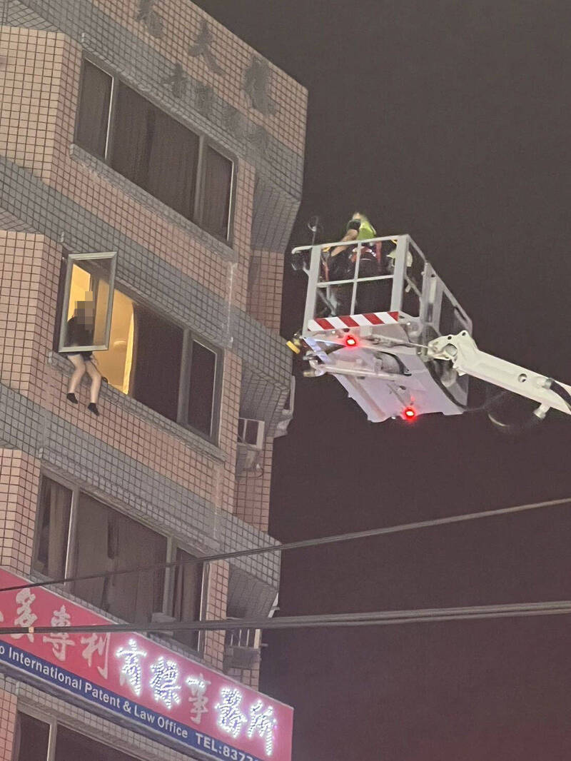女子跨坐大樓高樓窗台哭泣，消防救護人員搭乘雲梯車不斷對她安撫。（民眾提供）