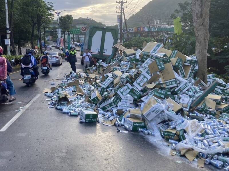 一輛載運啤酒的貨運聯結車今天上午6時許行經基隆市安樂區基金一路、石皮瀨圓環前，車上一箱箱罐裝啤酒突然掉落，造成基金一路往基隆市車輛嚴重回堵。（記者林嘉東翻攝）