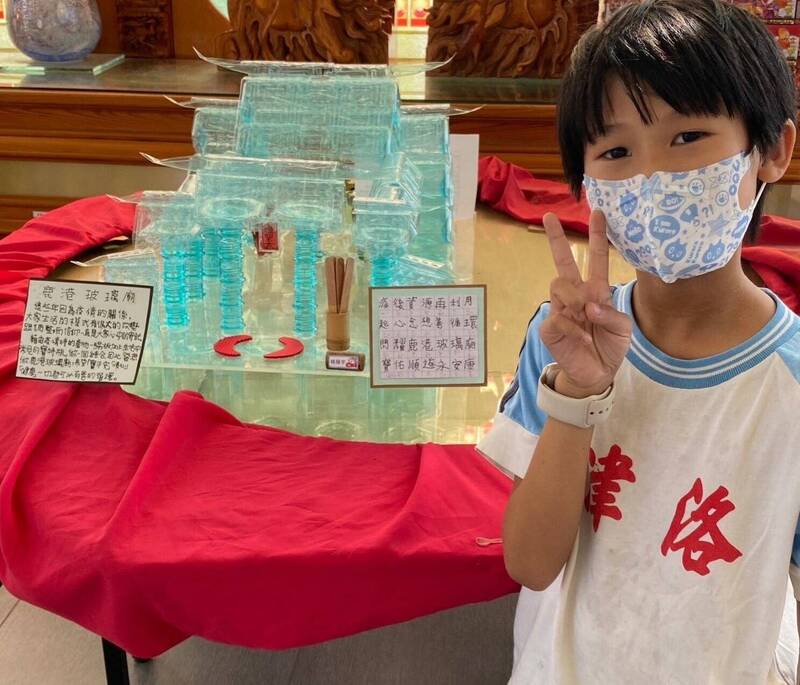 彰化縣鹿港鎮洛津國小學生楊展宇，年僅9歲完成寶特瓶玻璃廟作品拿到鹿港鎮資源回收創意比賽第一名，實現與天堂舅舅的約定。而作品即日起在玻璃廟展出，楊展宇開心見到作品與玻璃廟的夢幻相遇。（圖由李明潔提供）