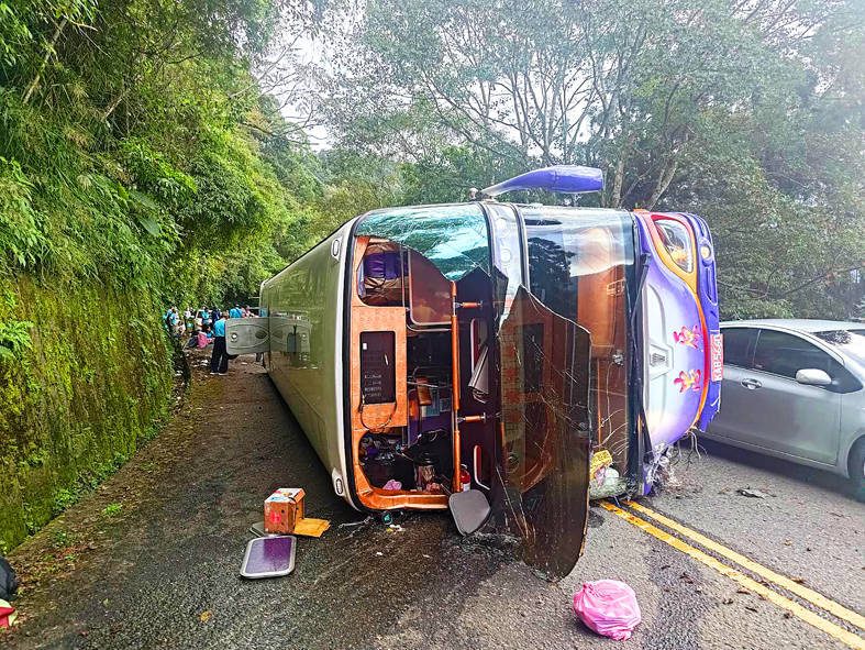 
A tour bus lies in the road after hitting a cliff face in Yilan County yesterday.
Photo courtesy of the Yilan County Fire Department