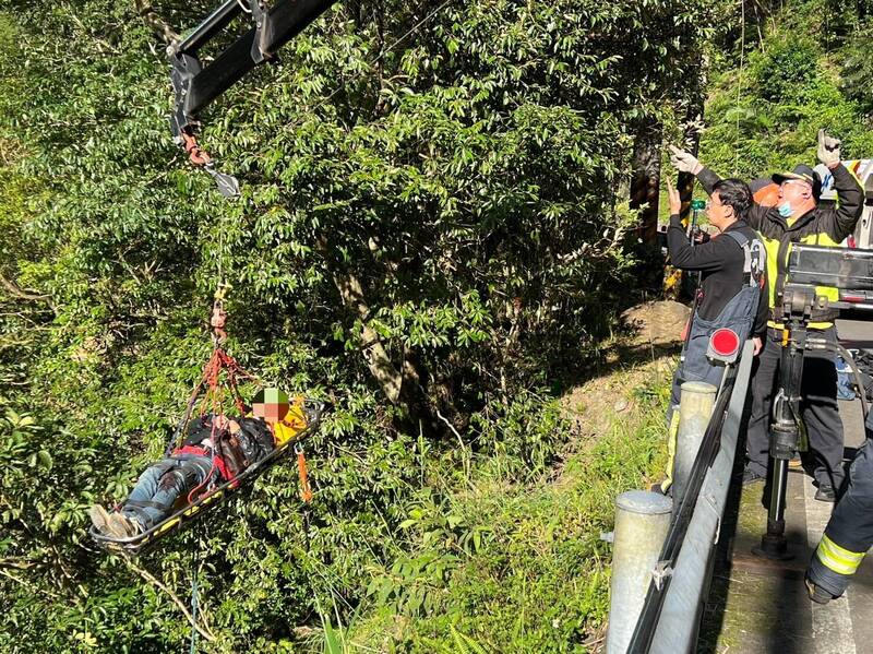 周男騎機車跑北宜公路坪林路段時，不慎自摔墜落20公尺山坡，警消趕抵將其固定吊掛救起 。（記者陸運鋒翻攝）