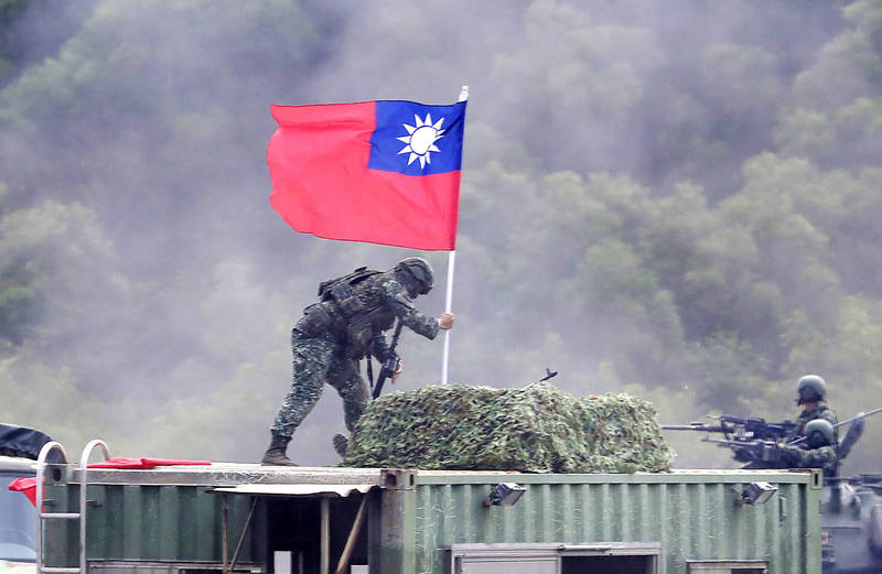 A soldier holds a Republic of China flag in Hsinchu County on Sept. 21 during drills that simulate integrated ground and air combat.
Photo: Chiang Ying-ying, AP