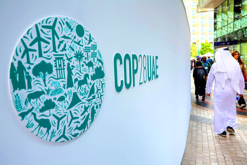People walk past a sign for the COP28 UN climate conference at Expo City in Dubai, United Arab Emirates, yesterday.
Photo: AFP