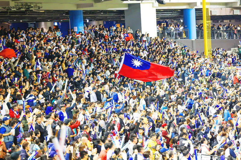 Baseball fans wave a Republic of China flag as they cheer for Taiwan during the Asian Baseball Championship opener in the Taipei Dome yesterday. Taiwan blanked South Korea 4-0 in the start of the first formal international tournament held at the newly opened indoor stadium. Only 17,000 fans were allowed in, far below the seating capacity of about 40,000, as the stadium is still being tested.
Photo: CNA