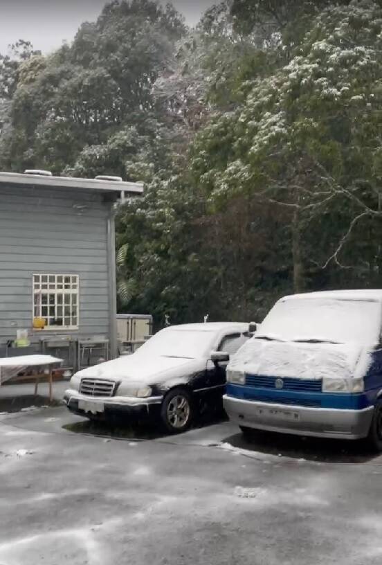 新北市烏來山區也下起白雪，在屋頂和車頂覆蓋一片薄薄的雪。（烏來區公所提供）