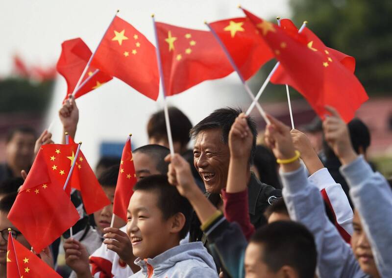 中国与新加坡达成免签协议，中国网路随即疯传新加坡境内会被罚款的生活相关规定。图为中国民众手拿中国国旗。（法新社）(photo:LTN)