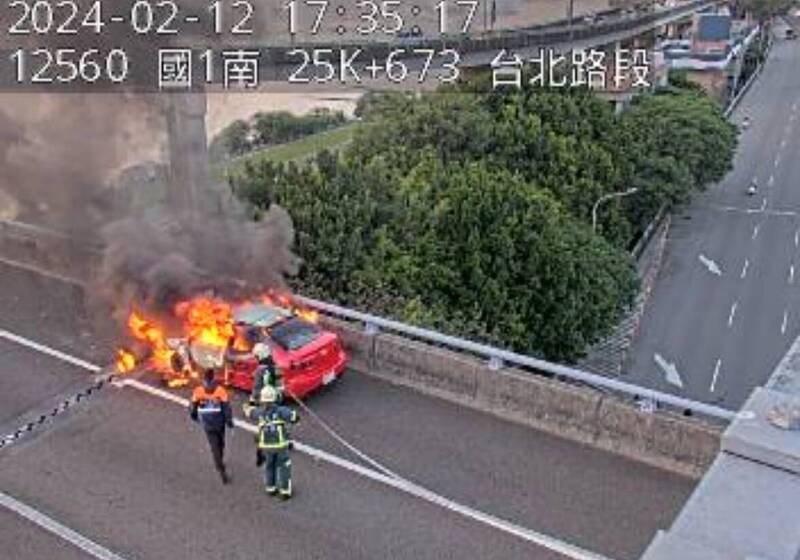 消防人員正與國道1號灌救火燒車。（記者徐聖倫翻攝）