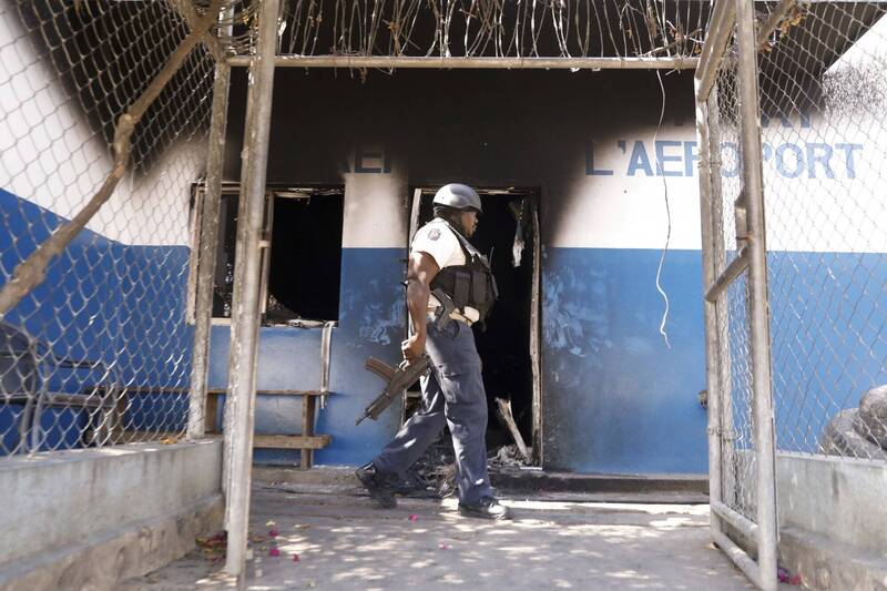 海地陷入暴乱，画面中全副武装的警察走过首都太子港一间警察局门前，这间警察局被焚毁，大半墙面燻黑。（美联社）(photo:LTN)
