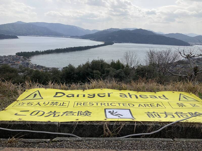 位在日本京都宮津市的「天橋立」傘松公園，因上月傳出有人跌落，園方事後在現場設置了一條巨型的黃色警告布條。（圖擷取自@riding_rate 社群平台「X」）