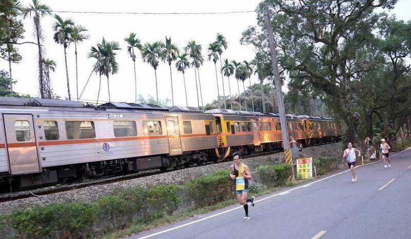 南投縣「集集鐵道半程馬拉松」登場，跑者在綠色隧道時，幸運踫到集集小火車行駛而過，呈現伴跑畫面，令人驚喜不已。（圖由南投縣政府提供）