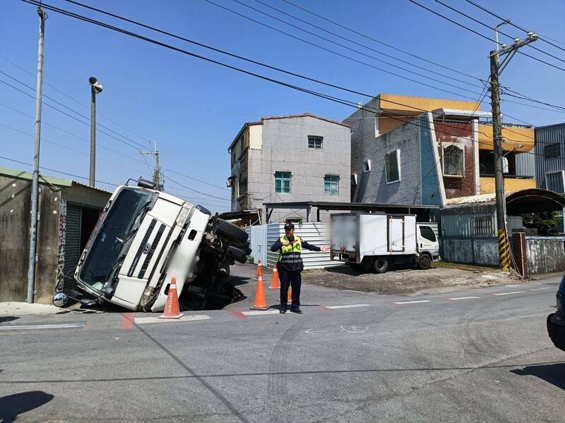 混凝土預拌車陷落路面後，往右傾倒撞擊一旁海產倉庫。（民眾提供）