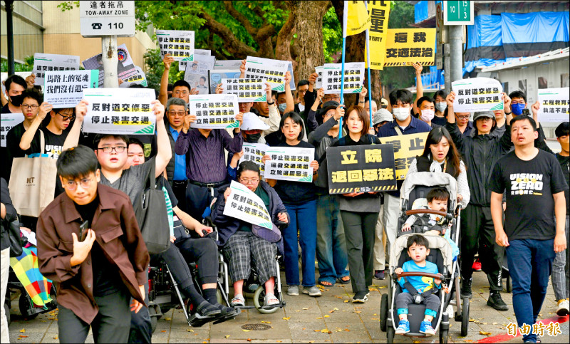 「行人零死亡推動聯盟」17日在全國7縣市發起同步快閃抗議，台北場於立法院前舉行，約300多人一同過馬路、高舉標語，籲退回修法草案。（記者羅沛德攝）