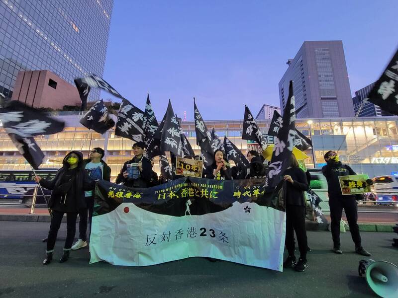 在日香港人在新宿高高舉「光復香港 時代革命」大黑旗，高喊「反對23條」等口號。（擷取自X平台）