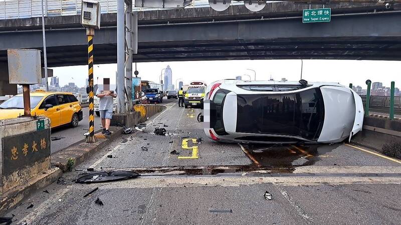 楊姓女駕駛開車自撞忠孝橋分隔島，汽車90度翻覆橫在路中。（記者徐聖倫翻攝）