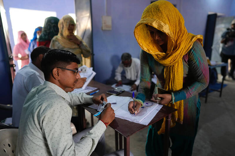 印度2024年大选选举人人数近9.7亿人，选举过程共需费时6周。图为印度公民签署文件准备投票。（美联社）