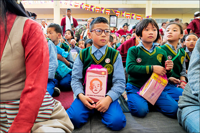出席活动的儿童手持介绍班禅喇嘛绘的相关书籍。（美联社）(photo:LTN)