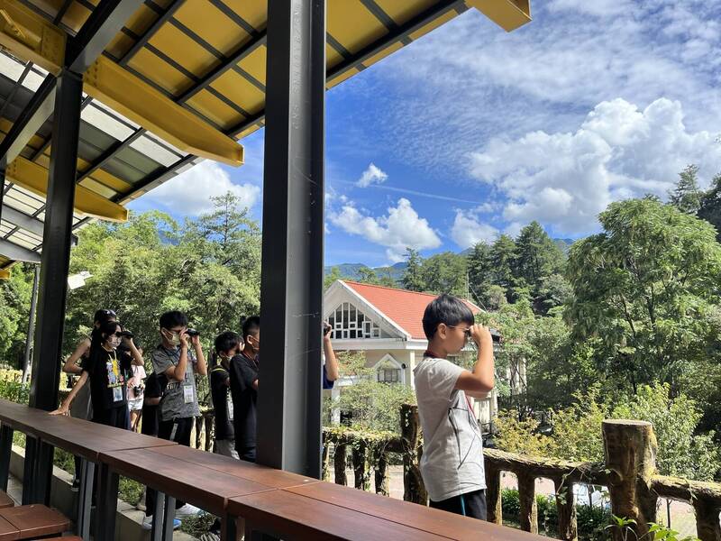 「野獸與牠們的產地－八仙山動物生態探索營」暑期營隊，學童拿起望遠鏡尋找樹梢的鳥兒。（圖由林業保育署提供）