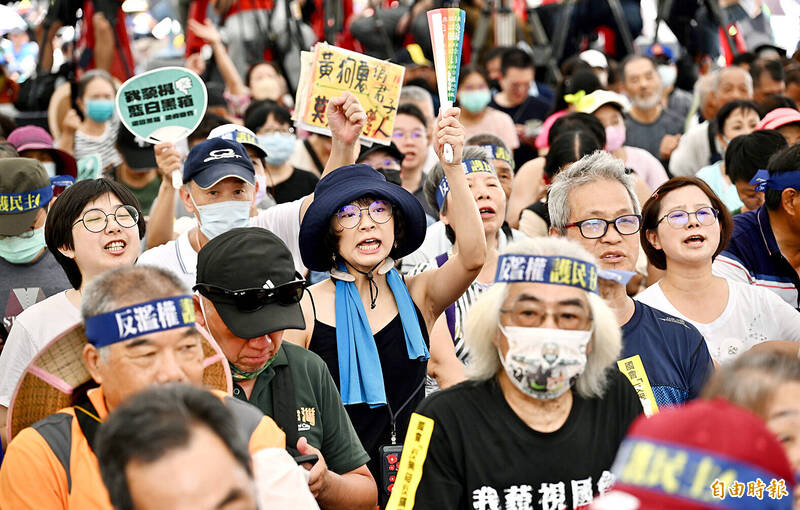 People hold signs opposing bills proposed by the opposition during a protest at the Legislative Yuan in Taipei yesterday. 
Photo: Lo Pei-de, Taipei Times
