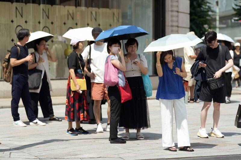 炎炎夏日，東京銀座商圈的行人紛紛撐傘抵擋毒辣的陽光。（美聯社）