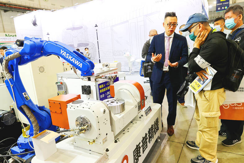 A sales representative introduces a robotic arm to visitors at the Taiwan International Machine Tool Show in Taipei on March 28.
Photo: CNA A sales representative introduces a robotic arm to visitors at the Taiwan International Machine Tool Show in Taipei on March 28.
Photo: CNA