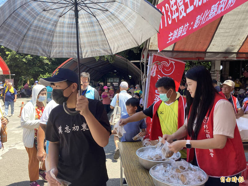 民眾在烈日下大排長龍爭拿美食。（記者顏宏駿攝）