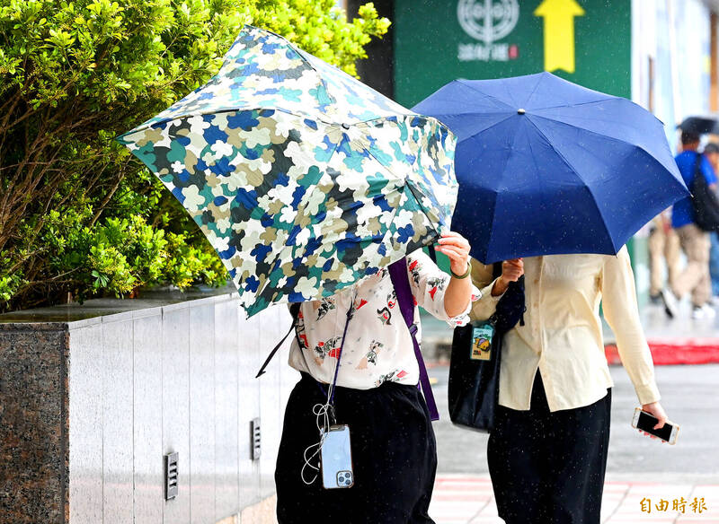 Two women hold on to their umbrellas amid strong winds in Taipei yesterday as Typhoon Gaemi approaches the nation. 
Photo: Wang Yi-sung, Taipei Times