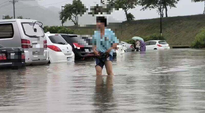 民眾捲褲管涉水要移車，但發現根本無法移動，面露無奈。（民眾提供）