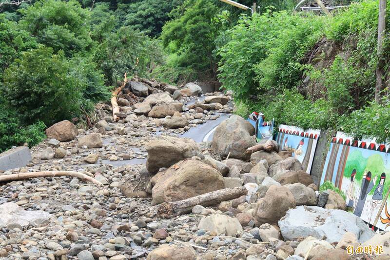 南投縣信義鄉羅娜村往筆石方向的聯外道路，因野溪暴漲，大小石頭被沖上岸阻斷道路。（記者張協昇攝）