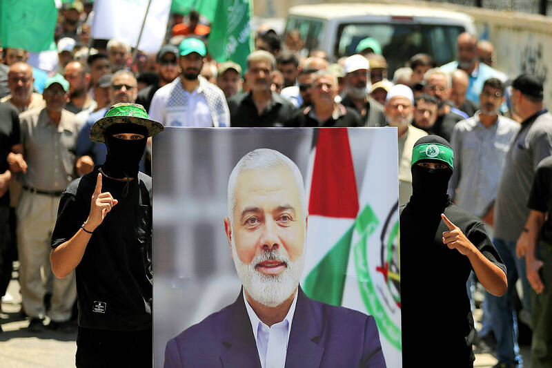 Hamas members hold a poster of Hamas political chief Ismail Haniyeh during a protest yesterday to condemn his killing, at al-Bass Palestinian refugee camp, in the southern port city of Tyre, Lebanon.
Photo: AP