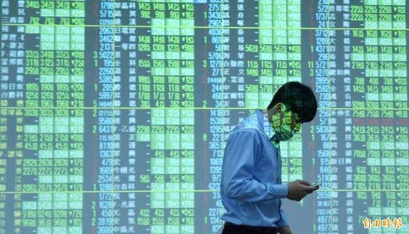 A man walks past an electronic stock board at a securities firm in Taipei in an undated photograph.
Photo: Taipei Times