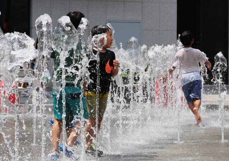 南韓持續遭熱浪侵襲，孩童2日在首爾市中心光化門廣場的1座噴泉玩耍、消暑。（歐新社）