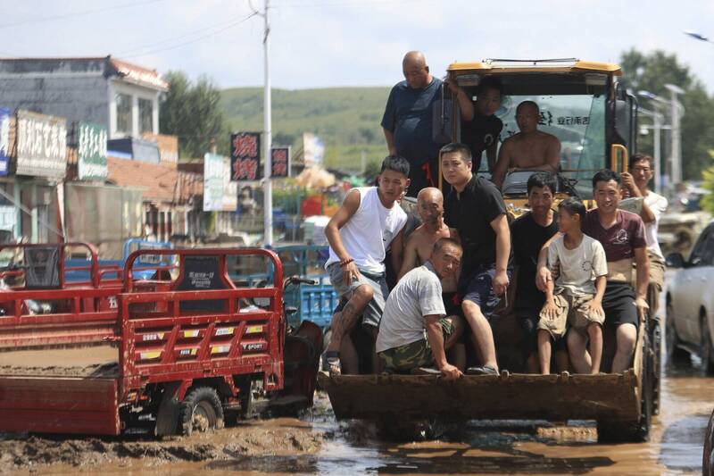 中國遼寧省葫蘆島市上週遭逢暴雨肆虐，圖為建昌縣黑山科鄉災民在雨後泥濘中靠推土機疏散。連續幾天大雨已知造成葫蘆島市11死14失蹤。（美聯社）