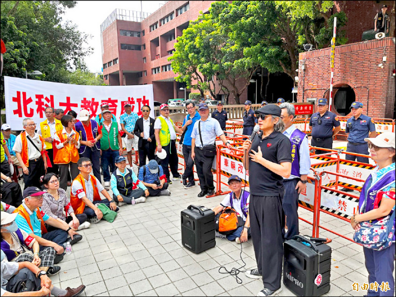 藝人包小柏（持麥克風者）為北科大校友，在國土署前帶領校友大喊「還我校地」以及領唱北科大校歌。（記者徐義平攝）