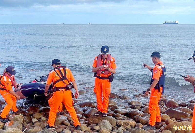 
Coast Guard Administration personnel and New Taipei City firefighters pull a rubber boat ashore near New Taipei City yesterday.
Photo copied by Wu Jen-chieh, Taipei Times