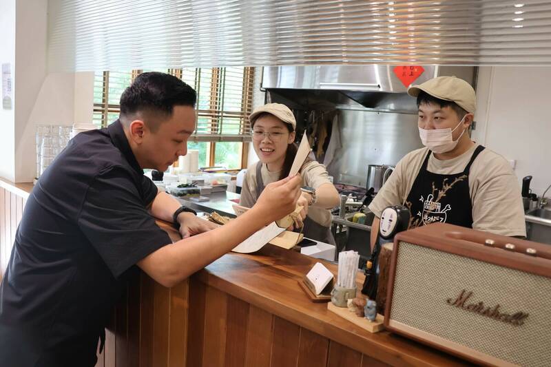 「小燉食室」開放透明的烹飪環境，令顧客安心食用，圖為青年局長張以理（左1）專程拜訪，與業者互動交流。（青年局提供）