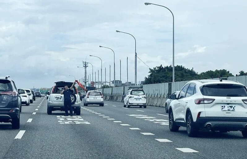 白色轎車國1北上拋錨駕駛人竟「人肉擋車」，嚇壞其他用路人。（民眾提供）