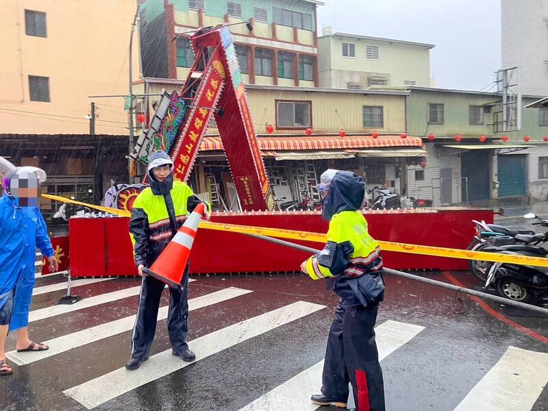 高雄鼓山二路與興隆路口，廟宇慶典的牌樓被強風吹垮，佔據整個馬路，警方於現場拉起封鎖線。（民眾提供）