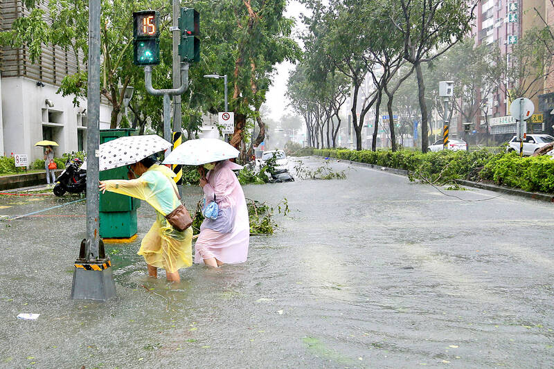 People holding umbrellas wade through a flooded street yesterday after Typhoon Krathon made landfall in Kaohsiung.
Photo: Ritchie B. Tongo, EPA-EFE