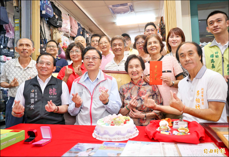 桃園市長張善政（左二）訪大溪百歲人瑞黃邱却（右二）祝壽，贈送金戒子等重陽賀禮，蛋糕旁邊是阿嬤參加長青田徑賽的獎牌。（記者李容萍攝）