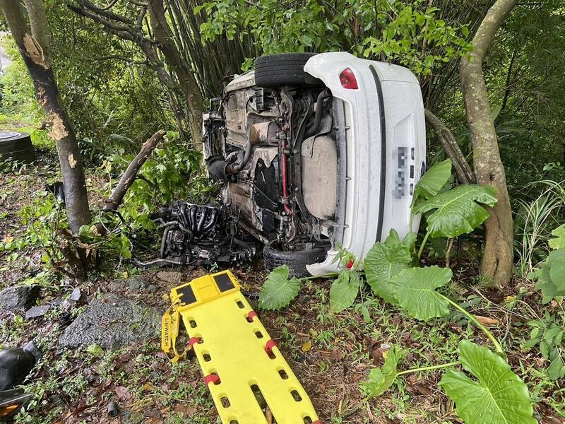 白色轎車衝進路旁草叢翻覆，駕駛一度受困車內。（記者吳昇儒翻攝）