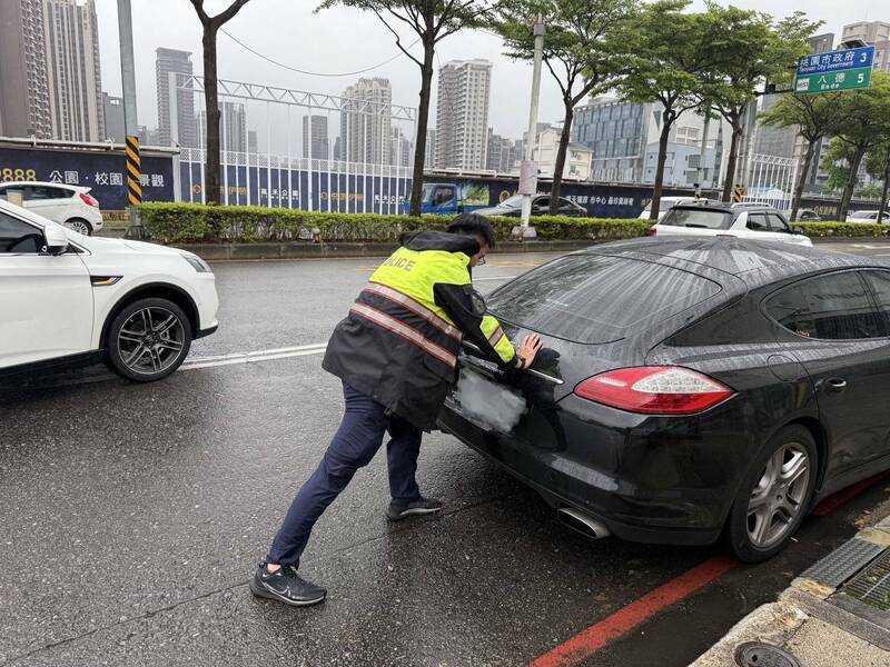 黑色保時捷雨天在南桃園交流道大興西路往桃園方向拋錨，員警巡邏經過幫忙推車解圍，過程中有熱心貨車司機加入，讓後方回堵的車流趕緊紓解。（記者鄭淑婷翻攝）