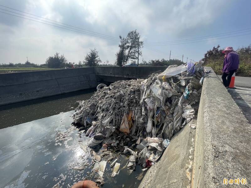 雲林縣四湖鄉海仔寮排水溝遭傾倒大量廢塑膠混合物，河道被堵住三分之一，影響水流。（記者黃淑莉攝）