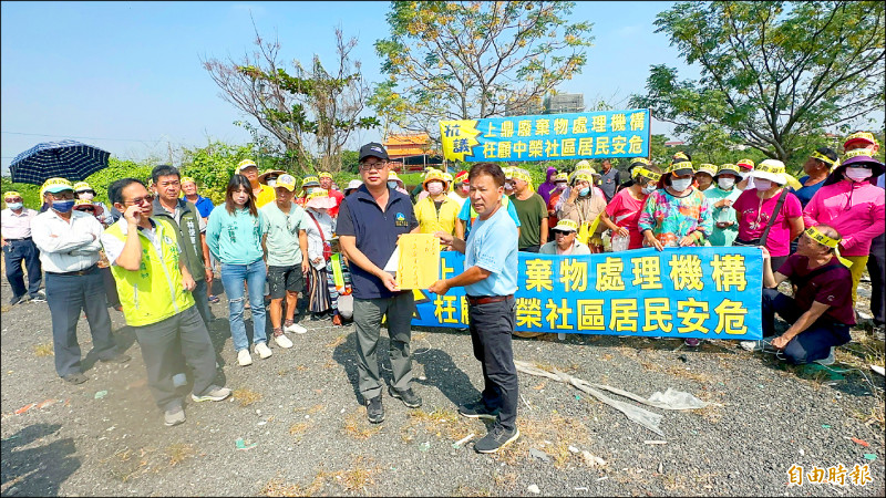 安定中榮里民拉布條抗議業者計畫擴大土資場，設置廢棄物處理機構，並由里長翁炳煙（左）代表遞交陳情書給市府官員。（記者劉婉君攝）