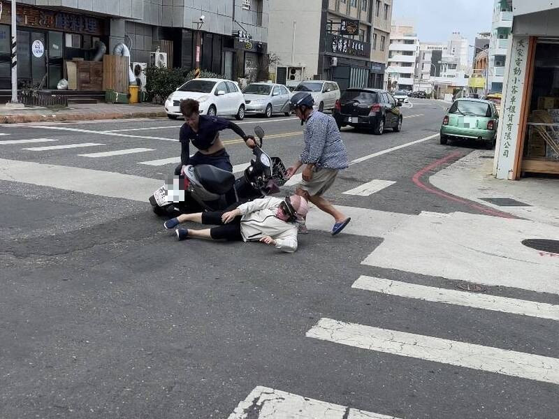 澎湖東北季風超強，馬公街頭有機車騎士騎車通過路口時竟強風吹倒，路人協助幫忙扶車。（民眾提供）