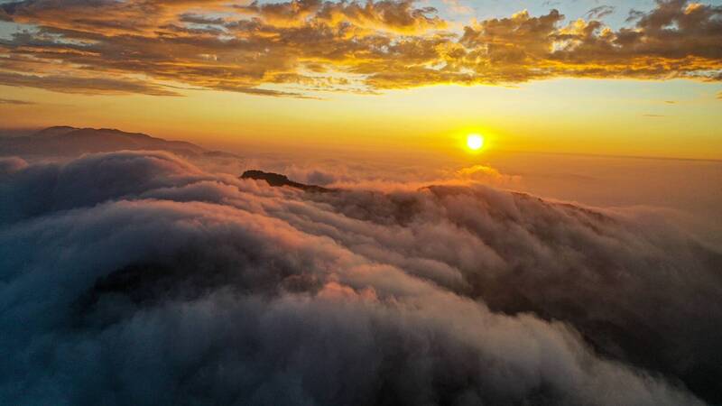 受東北季風與颱風外圍環流影響，南投鹿谷大崙山再現波瀾壯闊雲瀑，與豔麗火燒雲同框。（林建興提供）