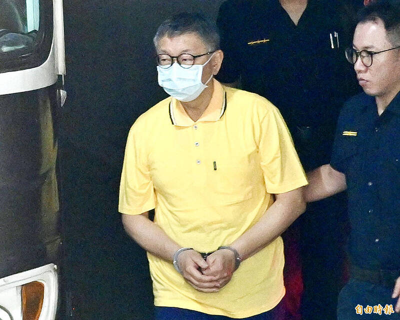 
Taiwan People’s Party Chairman Ko Wen-je is led in handcuffs for his first arraignment by the Taipei District Prosecutors’ Office on Sept. 10. 
Photo: Tu Chien-jung, Taipei Times