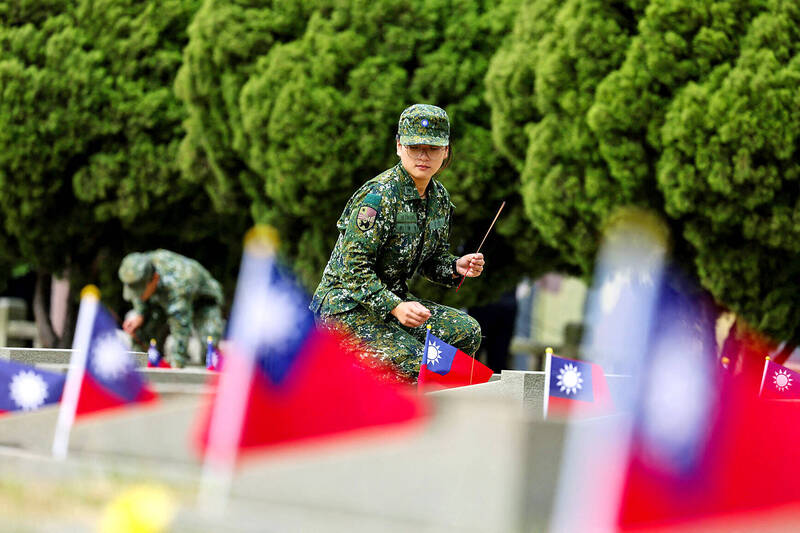 
A soldier places an incense stick on a grave at a public cemetery during a ceremony commemorating the 75th anniversary of the Battle of Guningtou in Kinmen County yesterday. 
Photo: I-Hwa Cheng, AFP