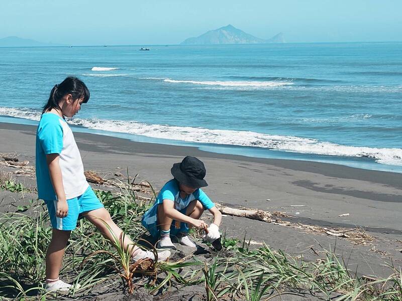 宜蘭縣小學生在五結海岸的加禮宛保安林，種下象徵希望的林投小苗，守護沿海保安林。（圖由林保署宜蘭分署提供）